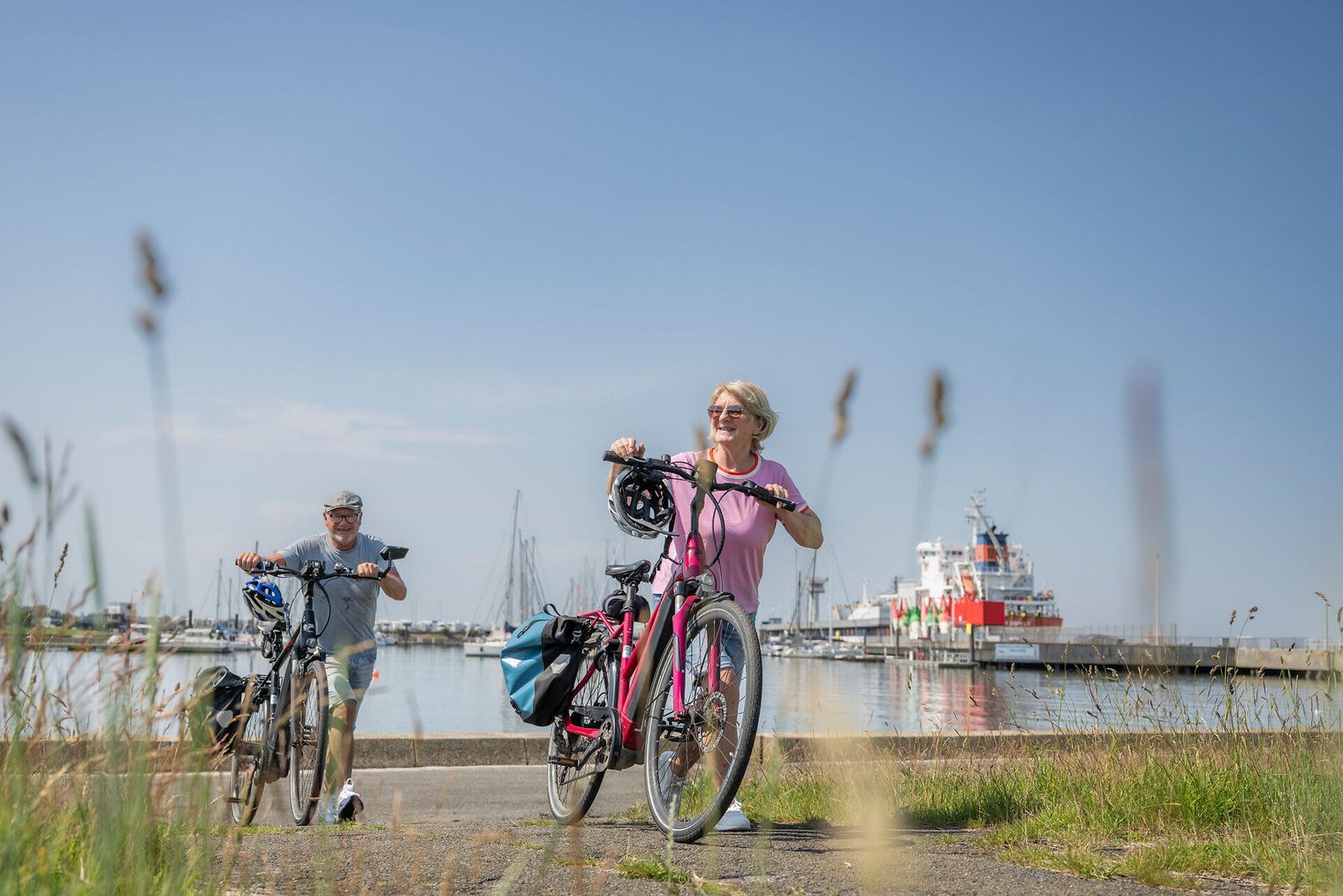 Aktive Radler schieben ihre Fahrräder am Yachthafen Cuxhaven