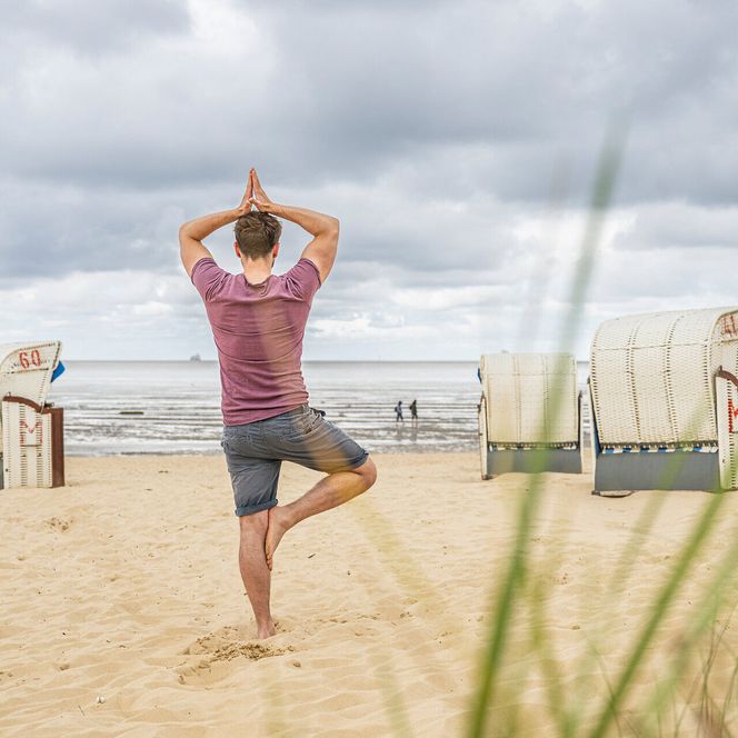 Ein Mann macht Yoga am Strand von Duhnen