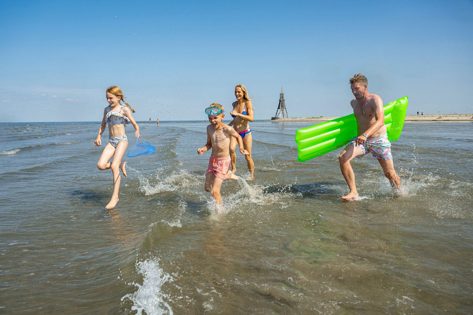 Eine Familie rennt mit Freude ins Meer am Strand von Döse