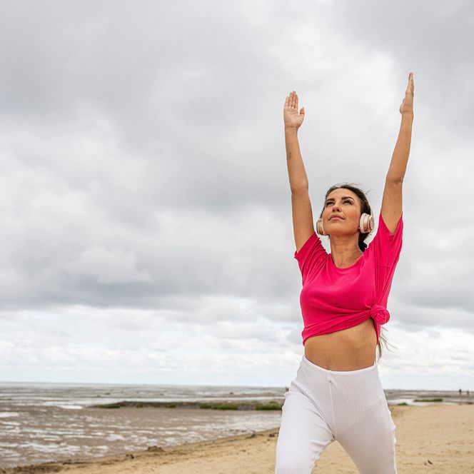 Eine Frau macht eine Yoga-Übung am Strand von Duhnen