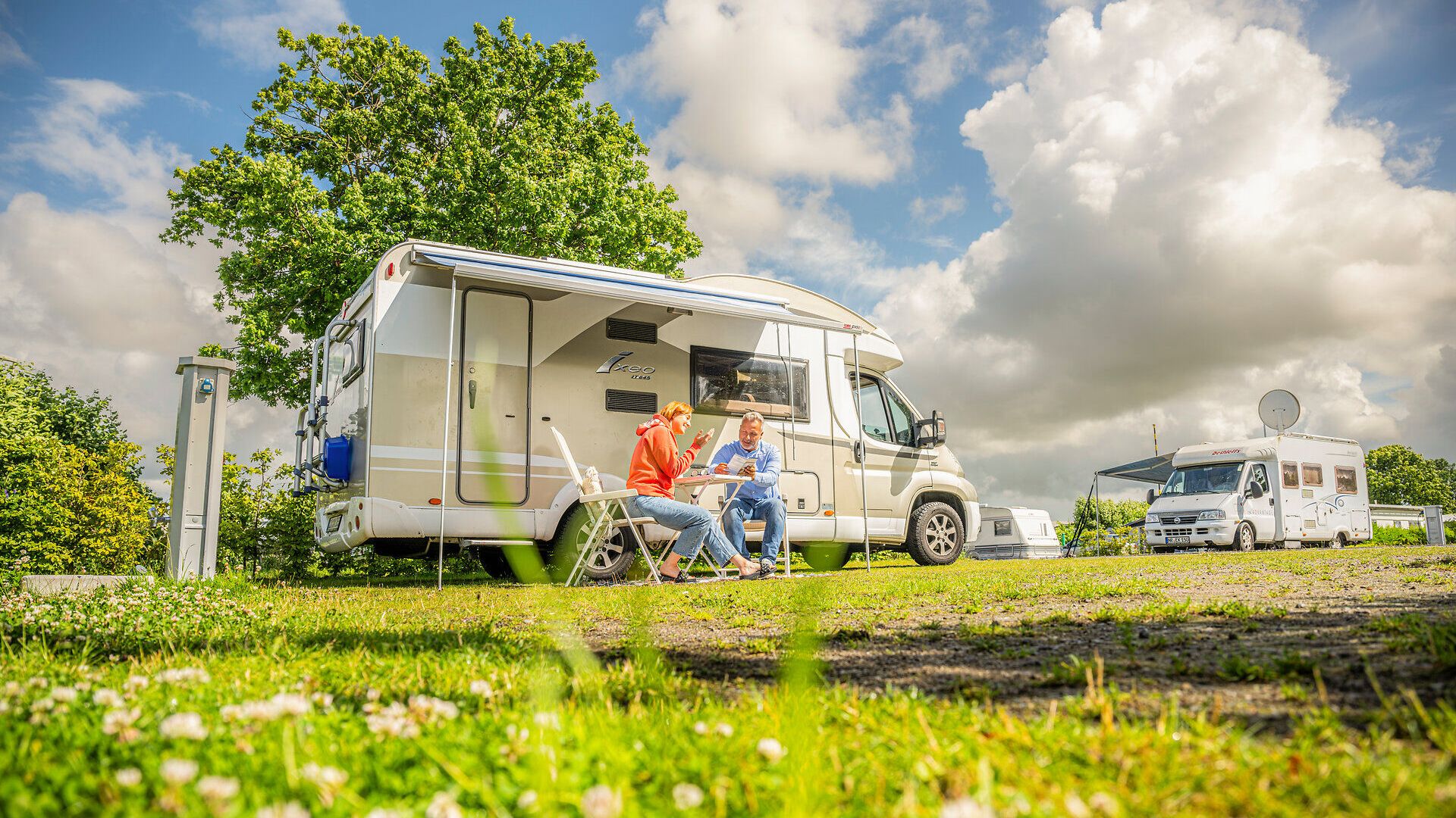 Ein Paar sitzt vor dem Camper auf dem Campingplatz in Altenbruch