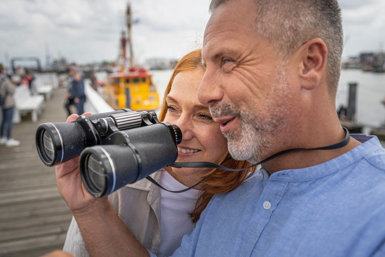 Ein Paar steht an der Alten Liebe und schaut durch ein Fernglas