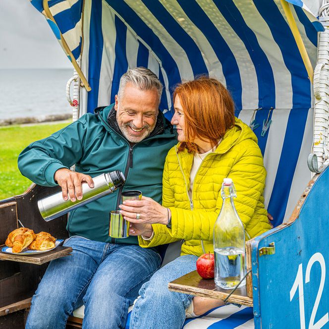 Ein Paar sitzt im Strandkorb und isst