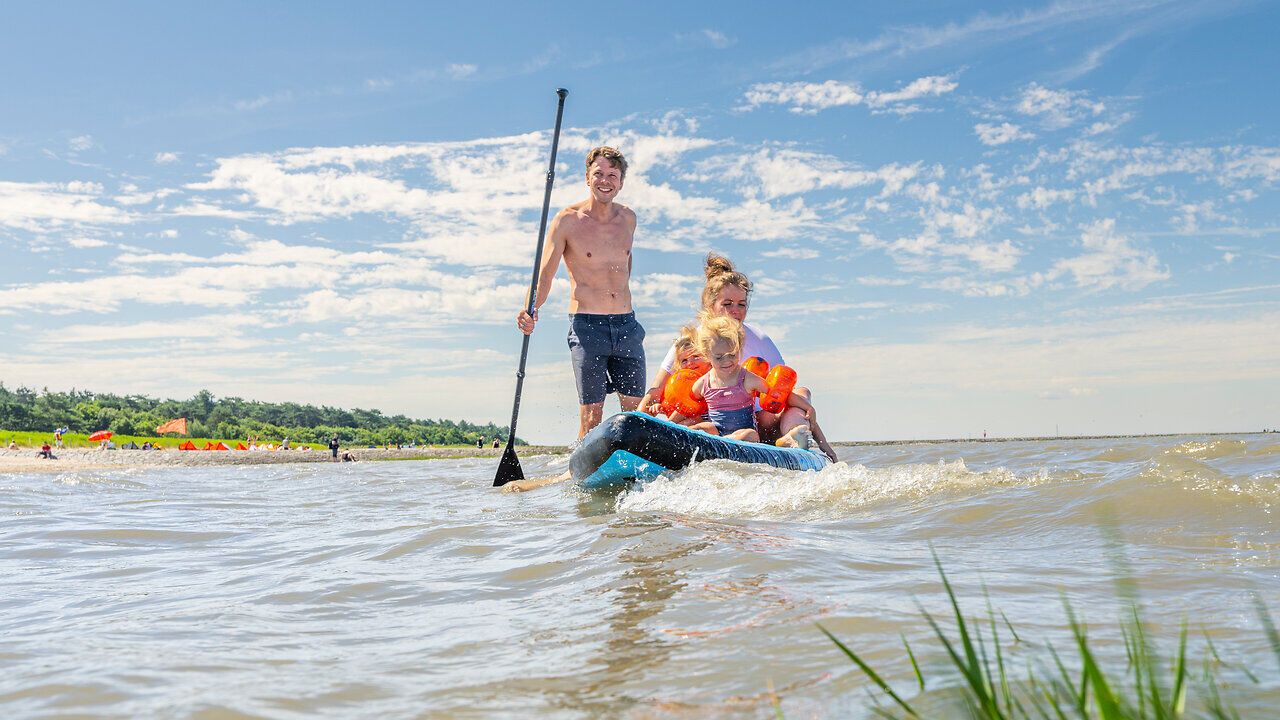 Eine Familie steht im Wasser am Strand von Sahlenburg