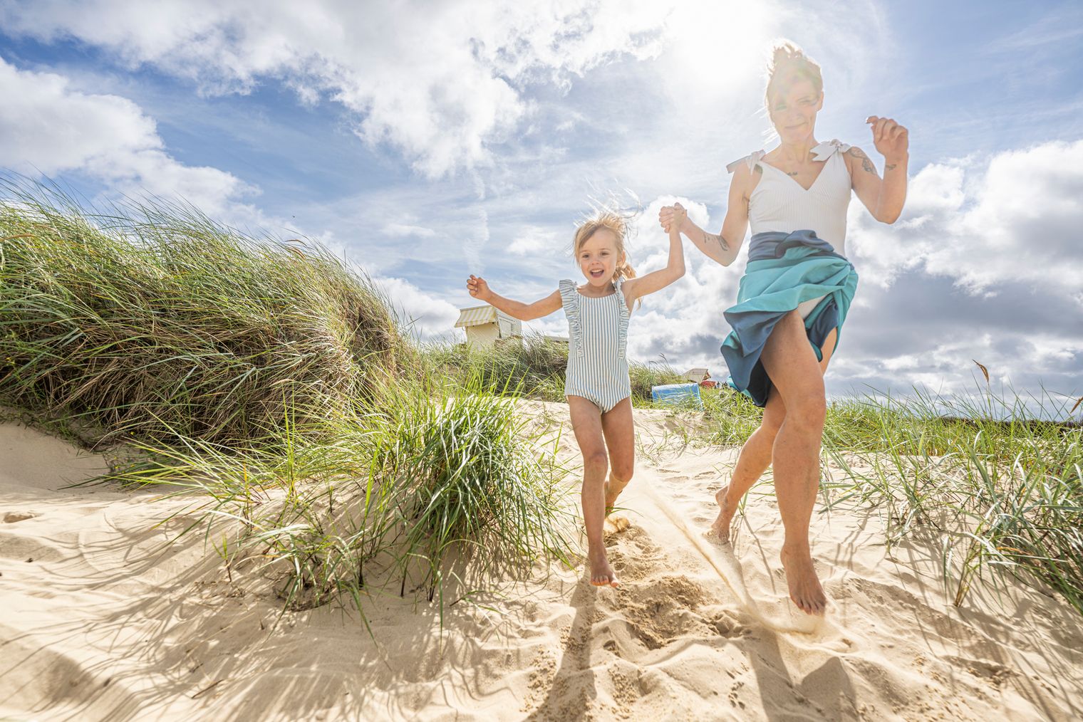 Kinder spielen am Strand, Mama im Hintergrund