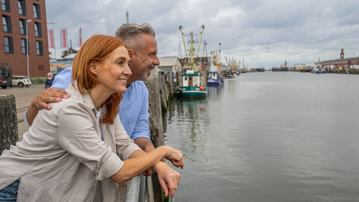 Ein Paar steht am Hafen und schaut auf das Meer